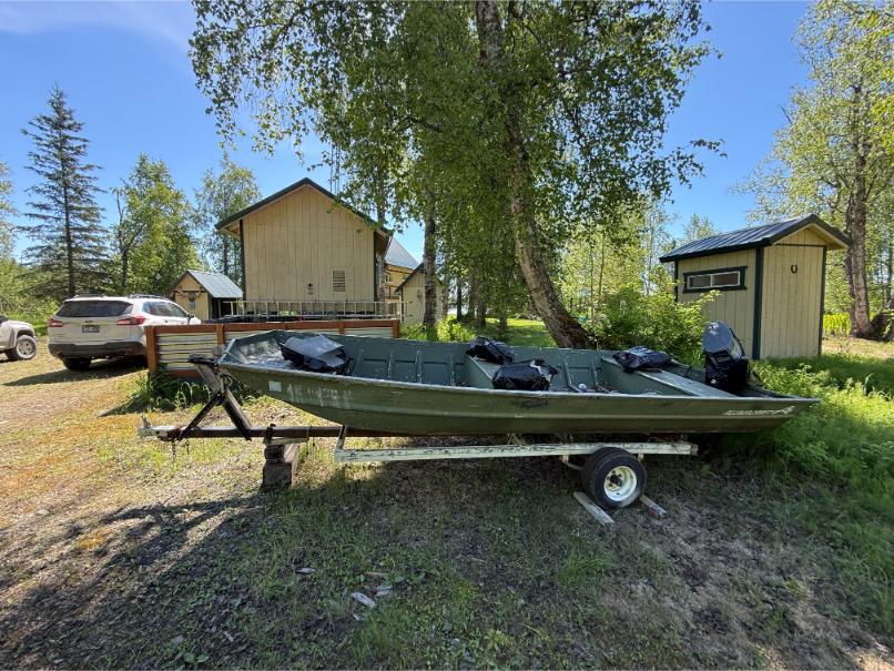 Remote Alaska cabin with boat and outbuildings illustrating the hidden costs of remote property ownership.
